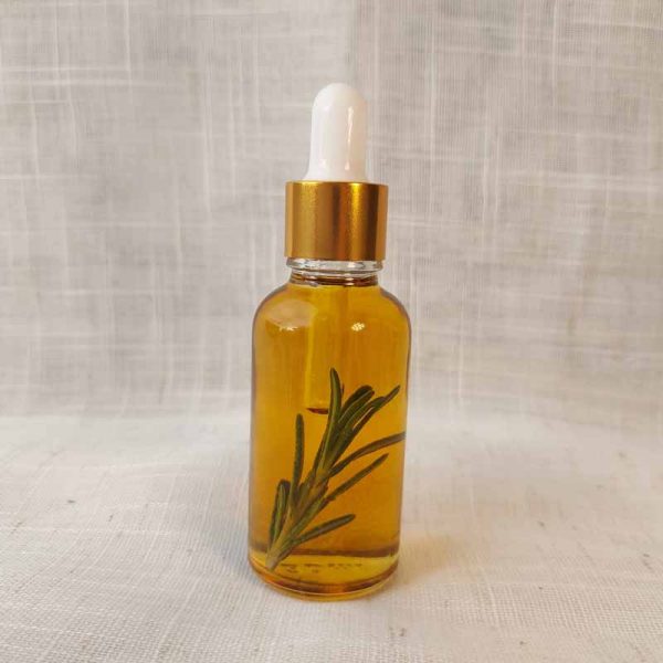 natural South Asian hair care. Glass pipette bottle with gold cap, containing golden colour hair and scalp oil with rosemary inside for your haircare routine.